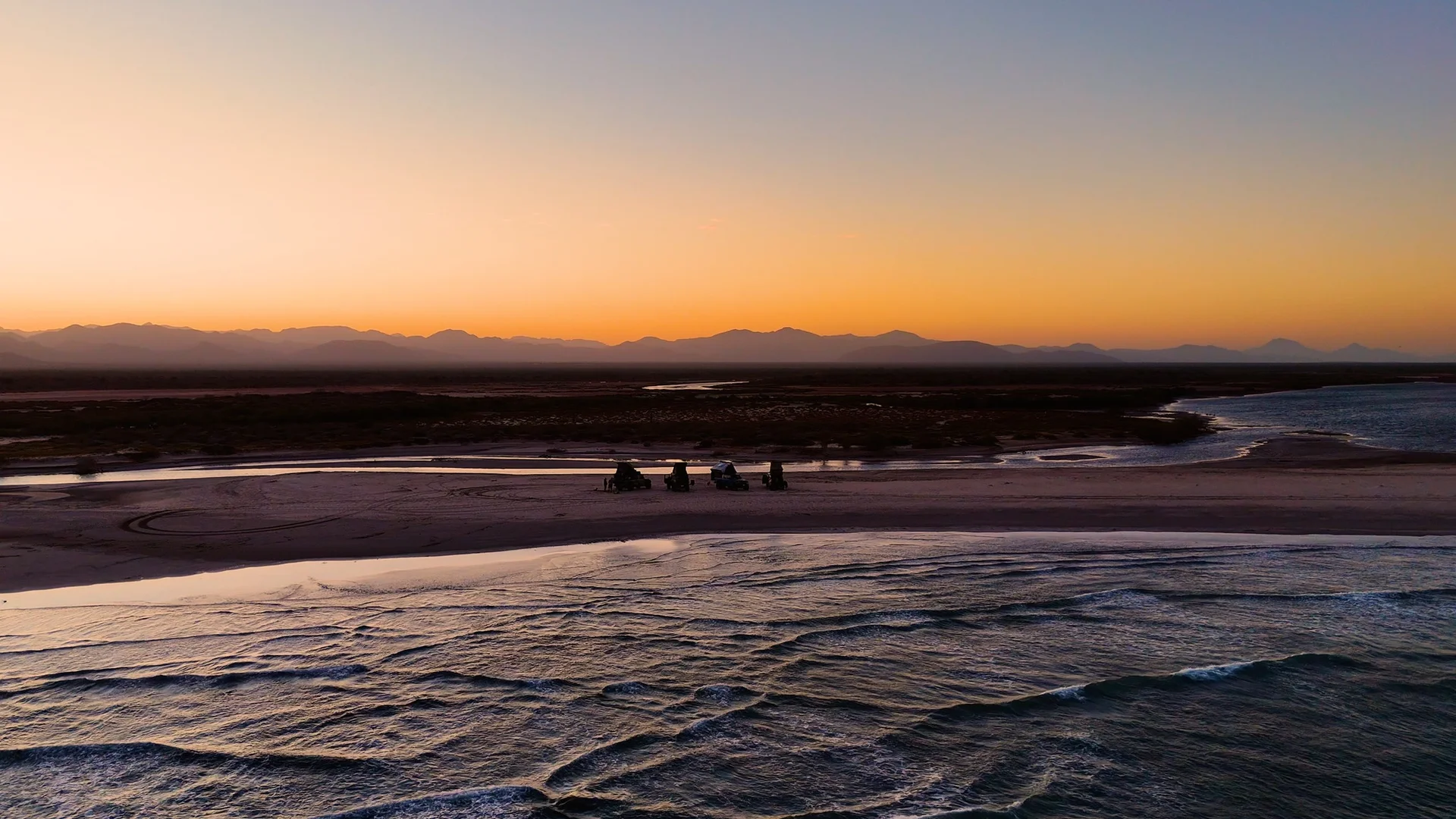 Off-grid timber shelter on beach in Argentina at sunset